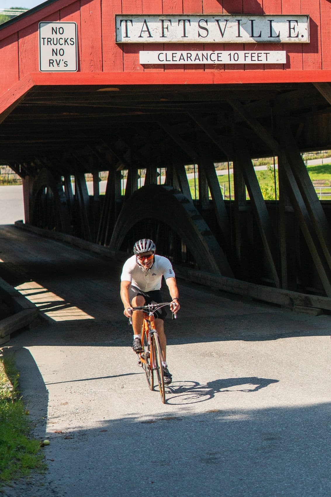 Judson riding a road bike through a Vermont covered bridge