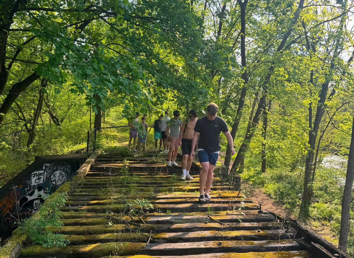 Friends walking an overgrown railway trestle in summer