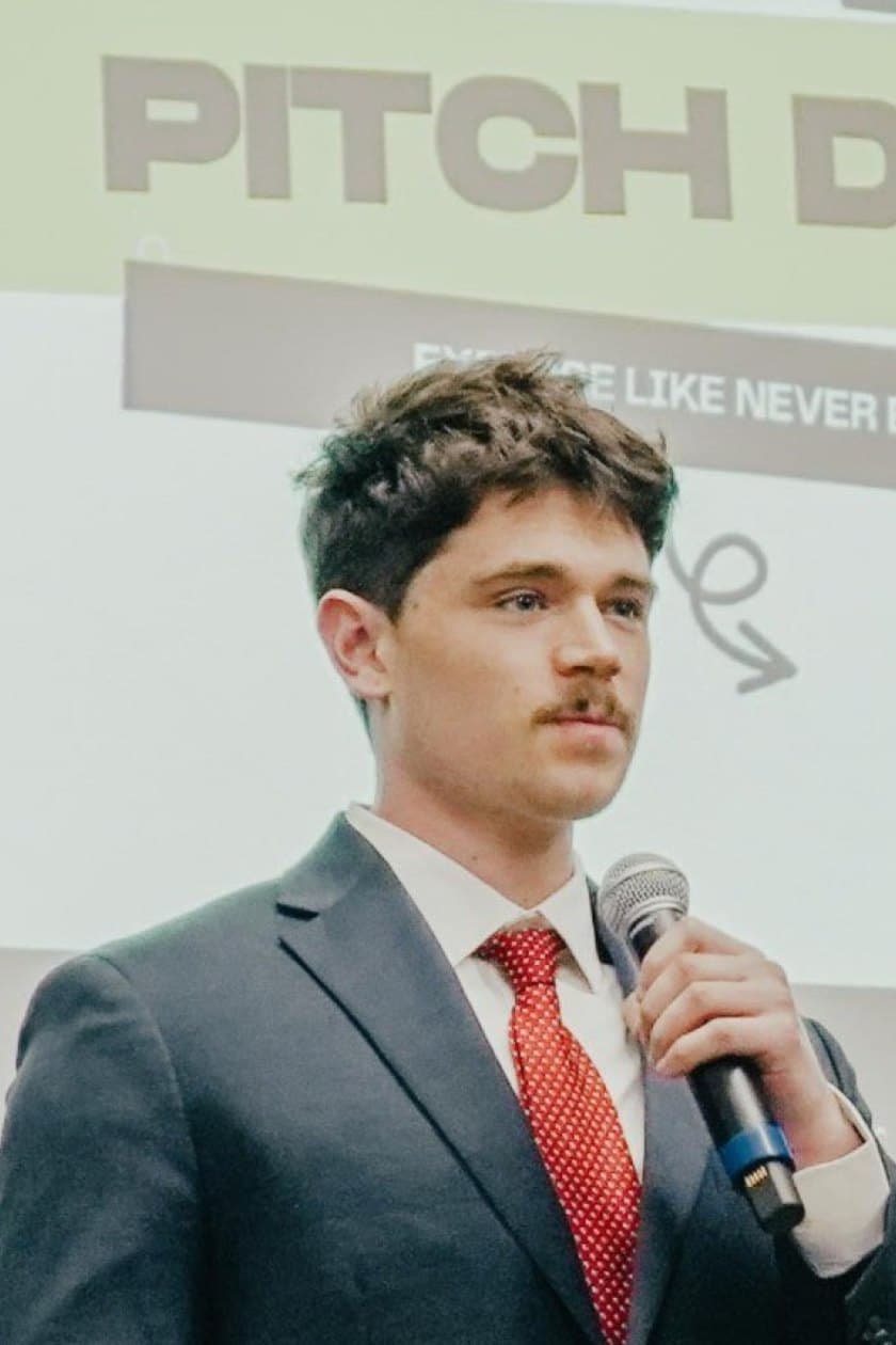 Judson Dunne mid-sentence on stage at the Big Idea Pitch Competition, microphone in hand