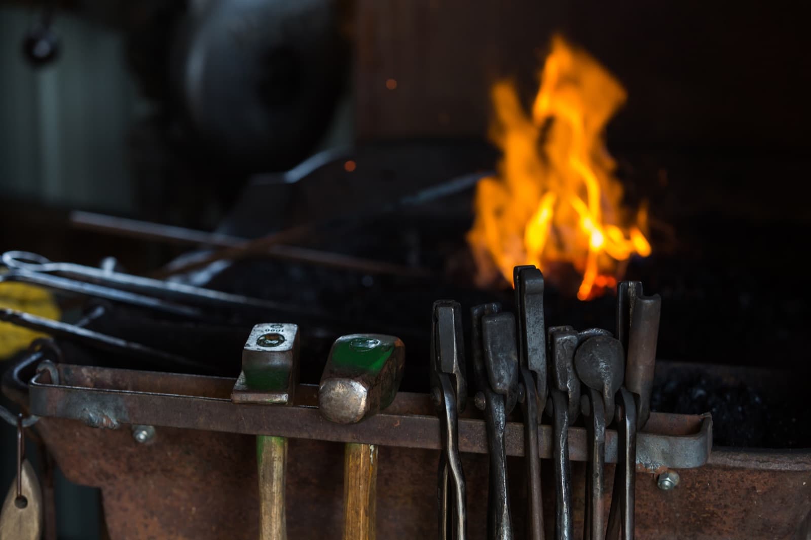 Coals burning in the forge with tongs laid across the fire