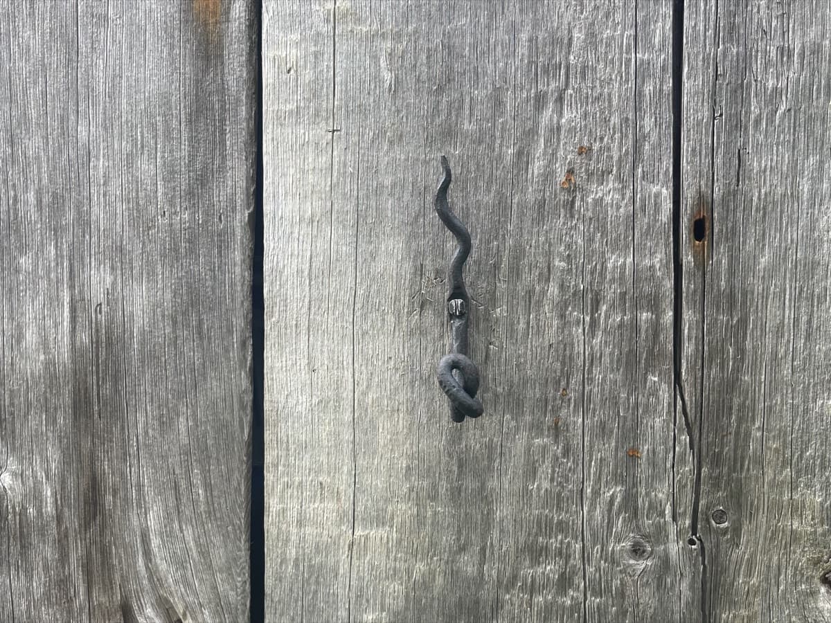 A hand-forged ivy hook with a flame top on barn wood